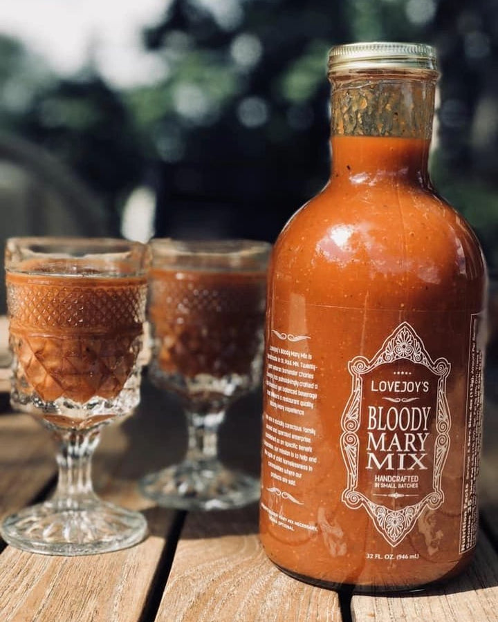 small bottle of bloody mary mix with two shot glasses
