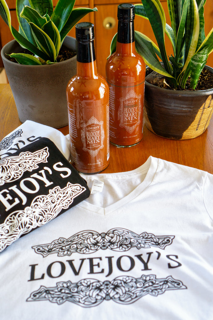 a white tshirt with two bottles of bloody mary mix sitting by the shirts