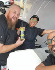 Lovejoy's employees holding up bottle of Bottle of Lovejoy's Chimichurri Bloody Mary Mix at market.