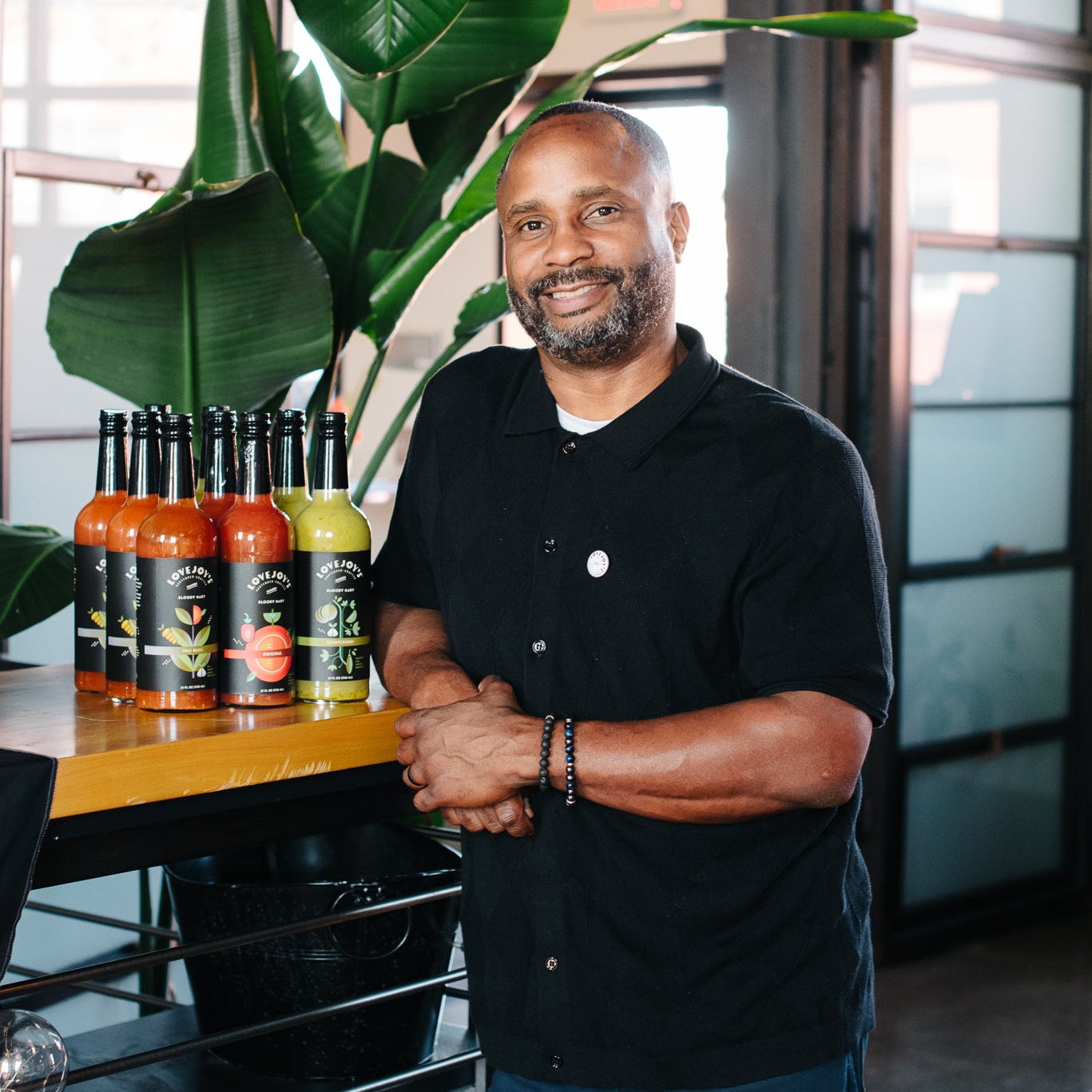 Man standing in a modern interior setting with bottles on a shelf