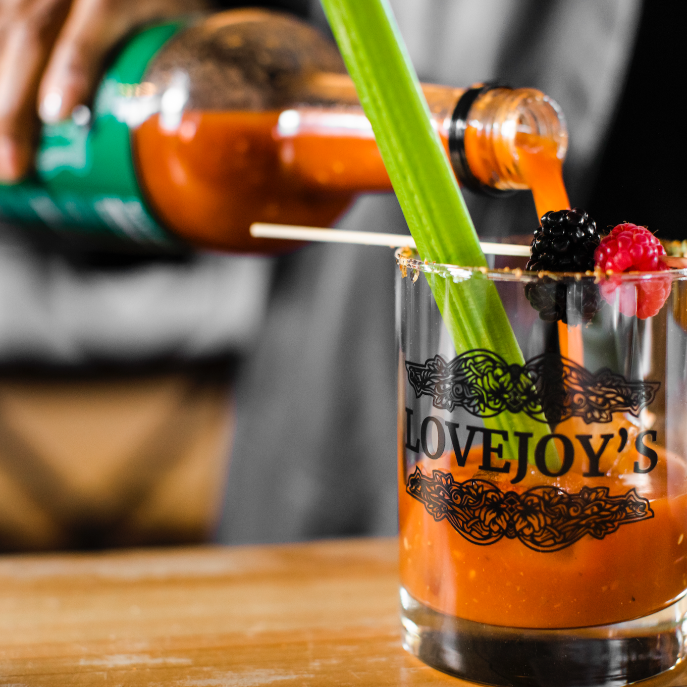 Mixing a Lovejoy's Bloody Mary in a glass with berries and celery.