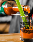 Mixing a Lovejoy's Bloody Mary in a glass with berries and celery.