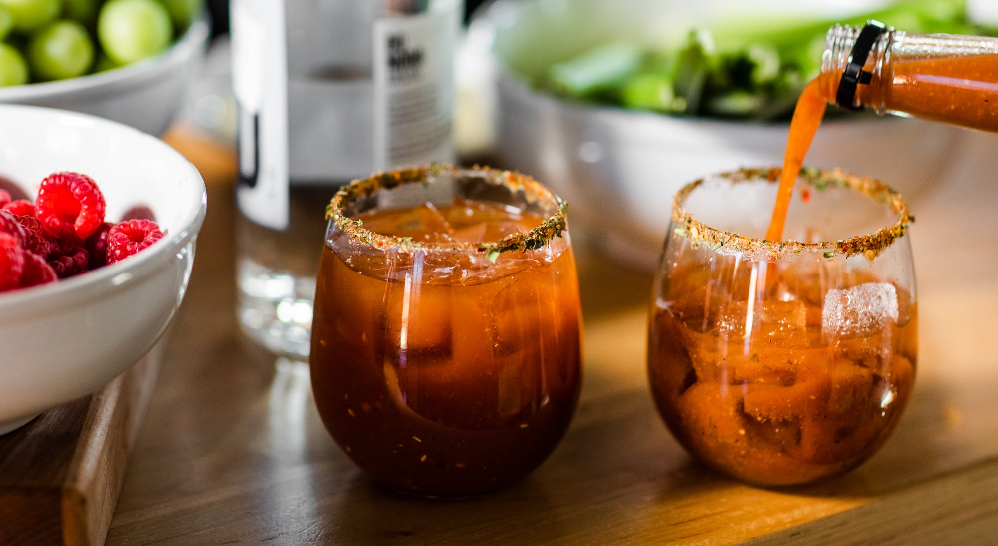 Pouring a Lovejoy's Bloody Mary into a glass with rim seasoning.